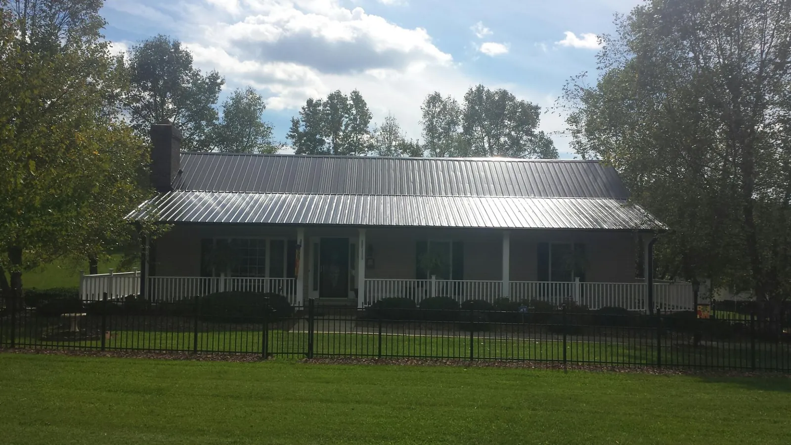 Gray metal roof on a brick ranch with a full width front porch — Gutter Guard Installation work by our crew in Vandalia