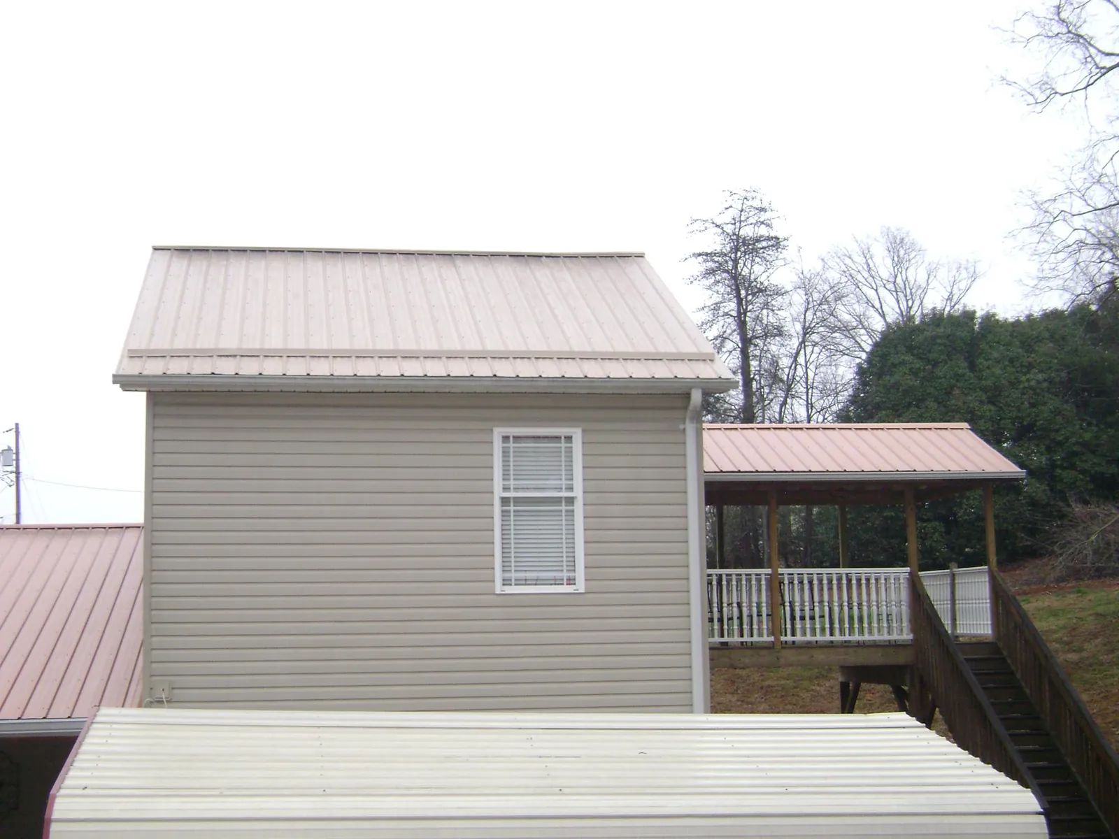 Tan metal roofs on a two story addition and attached porch, from a Roof Replacement job in Vandalia