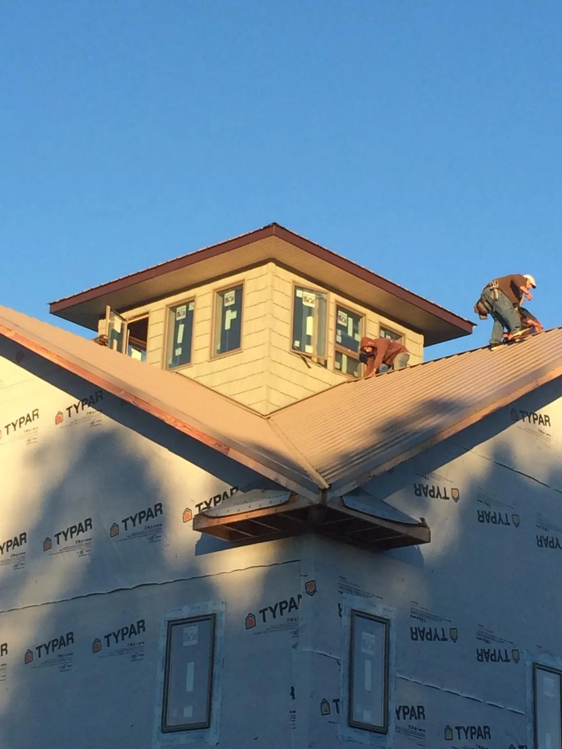 Roofers working around a rooftop cupola on a new metal roof at sunset — Roof Waterproofing in Vandalia by Roofing Brothers